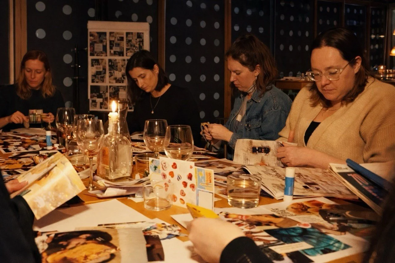 People sitting at a table looking at photographs during a gathering in a dimly lit room with a lit candle