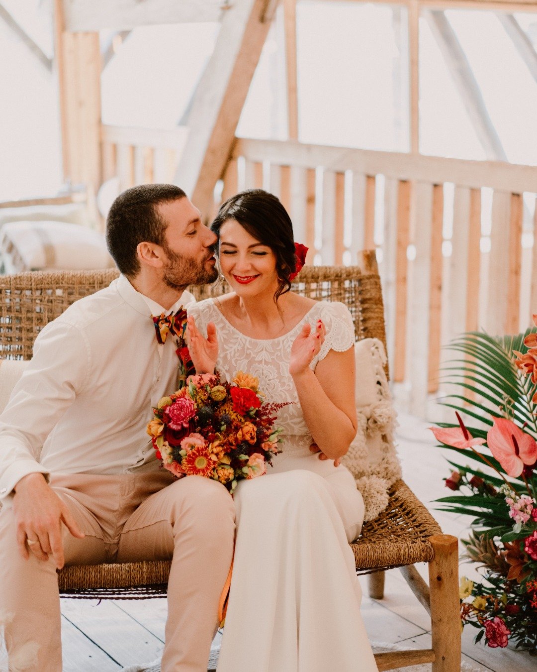 Un couple lors d'un mariage, la femme tenant un bouquet de fleurs colorées, la scène décorée avec des fleurs