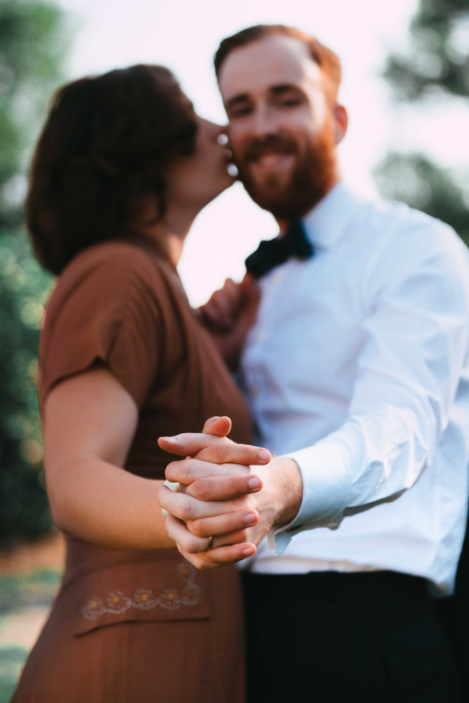 Un couple qui danse, la femme donne un baiser sur la joue de l'homme, qui sourit.