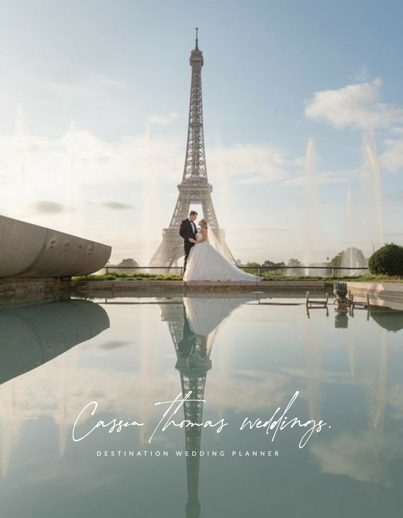 Un couple en mariage devant la tour Eiffel à Paris, avec un reflet dans l'eau devant eux, au coucher du soleil.