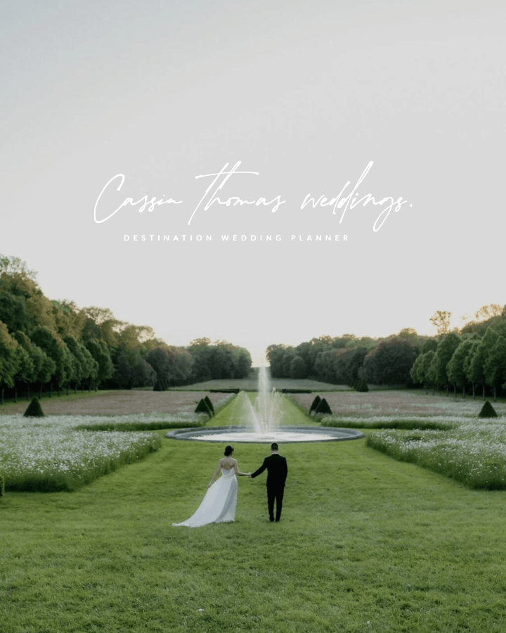 Une photo d'un couple en mariage marchant dans un jardin avec une fontaine, entouré d'arbres, avec un texte 'Cassin Thomas weddings. Destination wedding planner'.