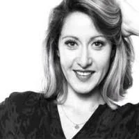 Portrait d'une femme avec des cheveux mi-longs, souriant, portant un haut noir.