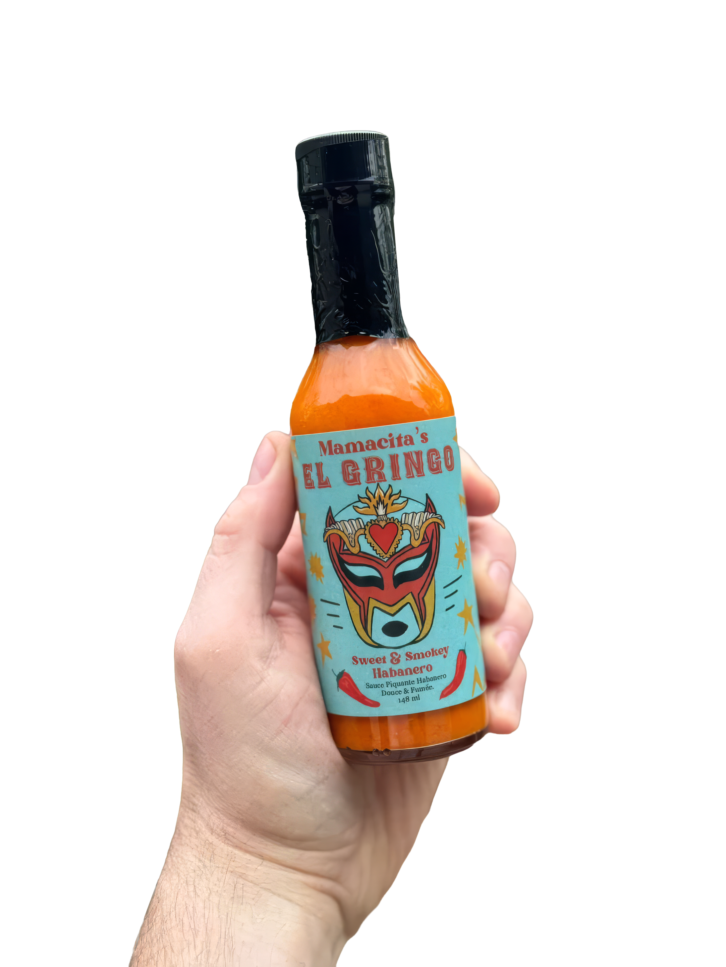 Hand holding a glass bottle of hot sauce with a colorful label featuring a lucha libre mask and chili peppers, labeled 'Mamacita's El Gringo,' described as sweet and smoky habanero flavor.