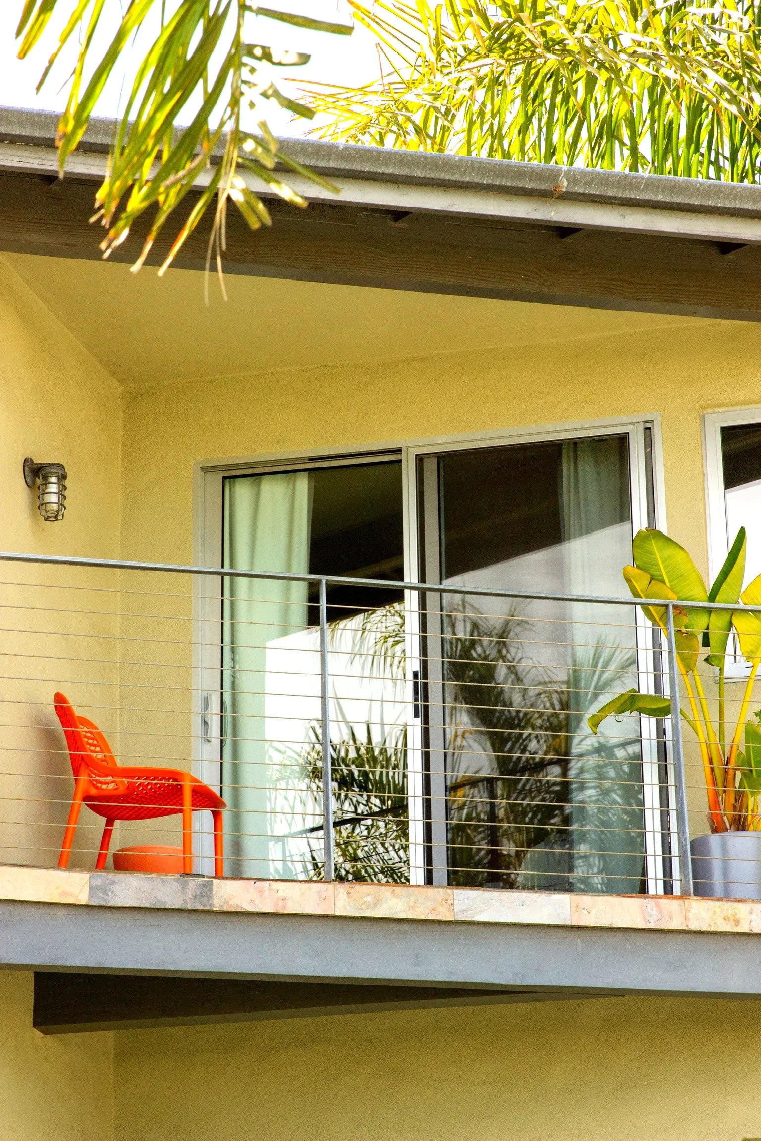 Private balcony with orange chair and tropical palms at The Malibu Motel Malibu CA