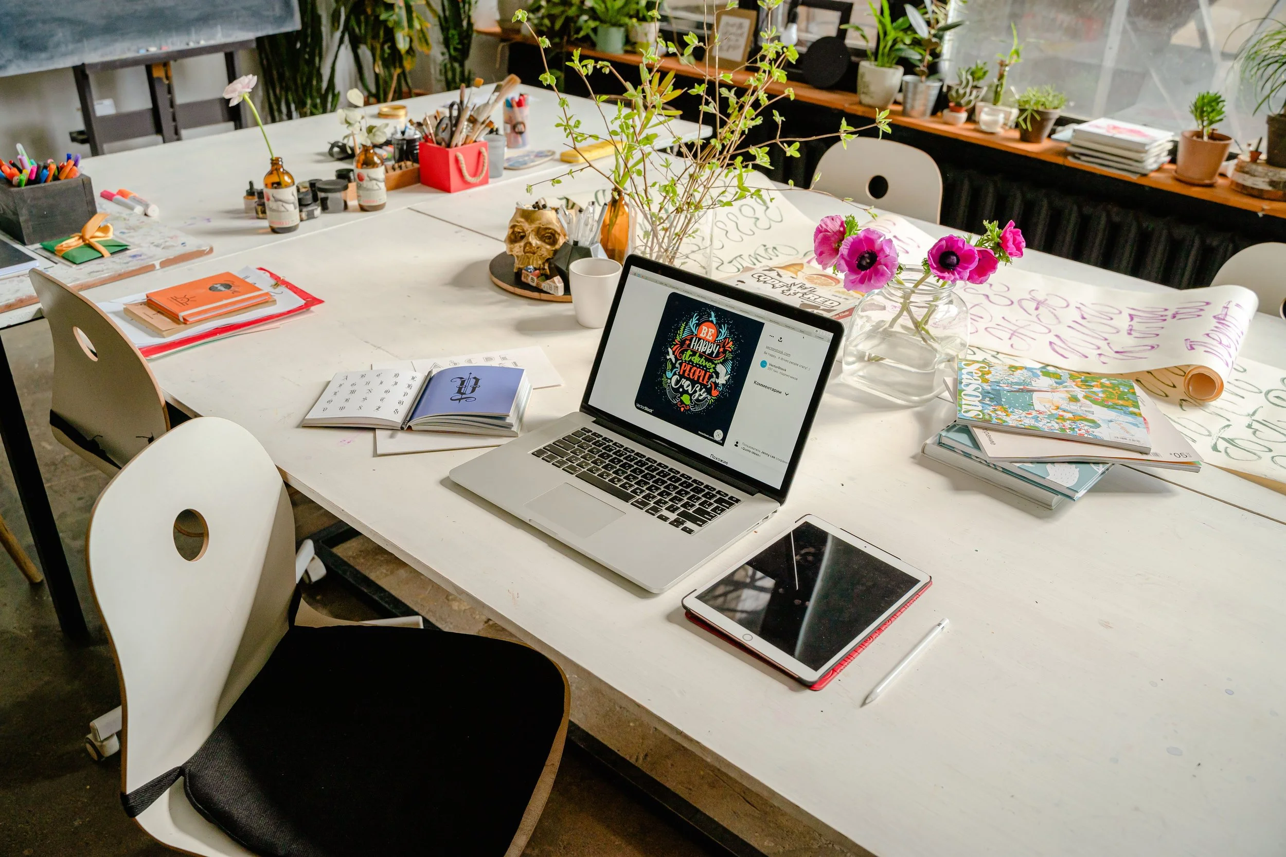Laptop on a workspace in a colourful office decorated with flowers and creative details
