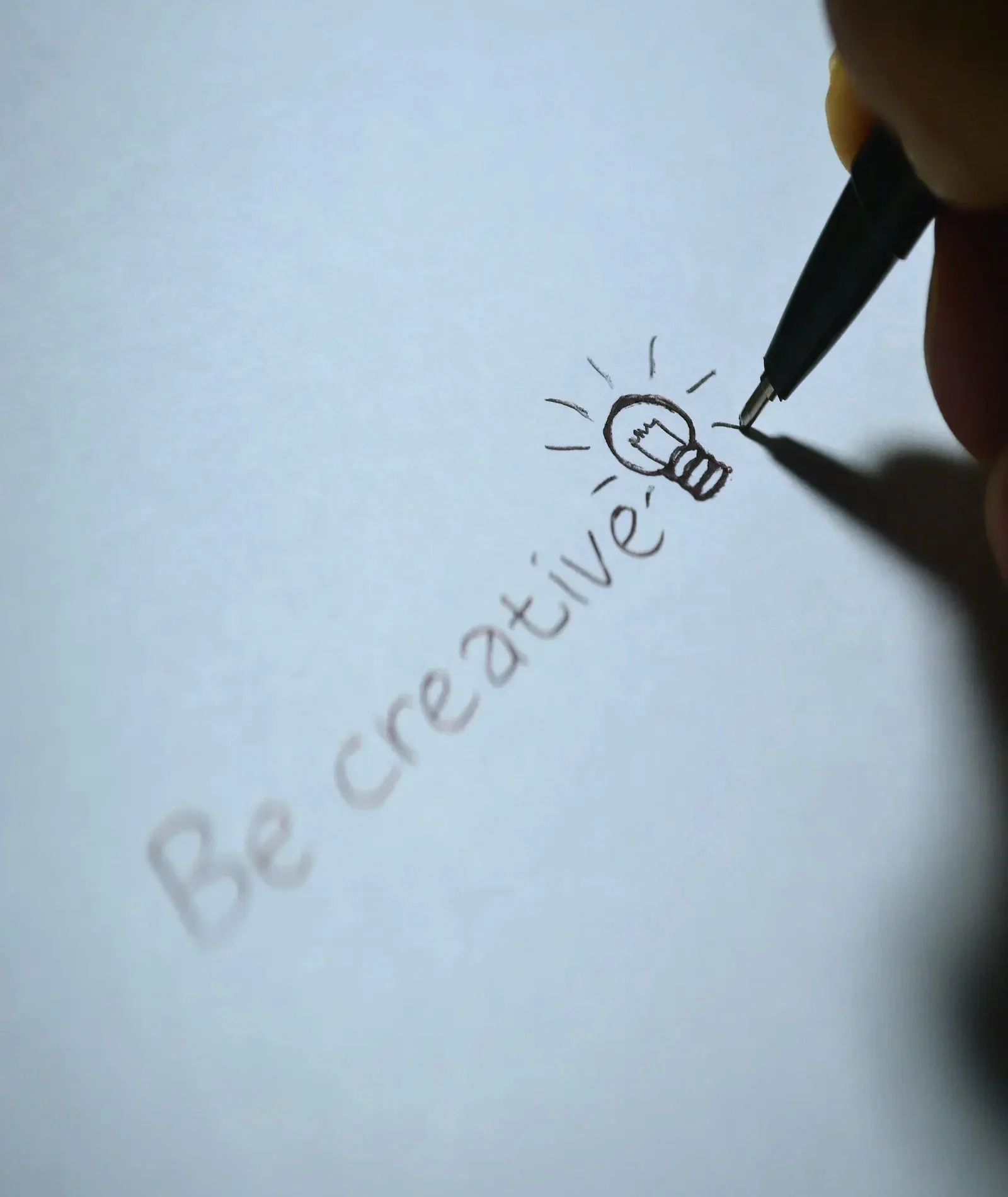 Handwritten "Be Creative" message with a light bulb drawing on a piece of paper
