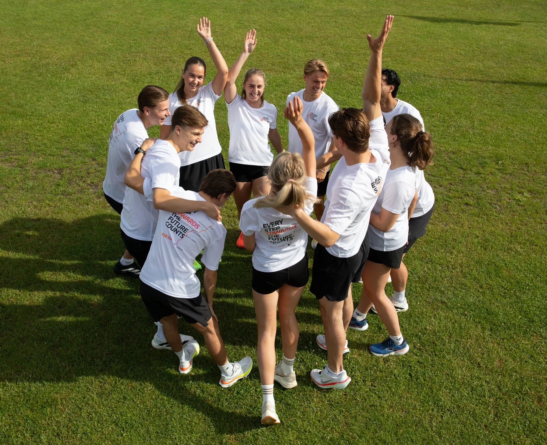 Groep lopers in sportoutfits vieren een overwinning op een grasveld.
