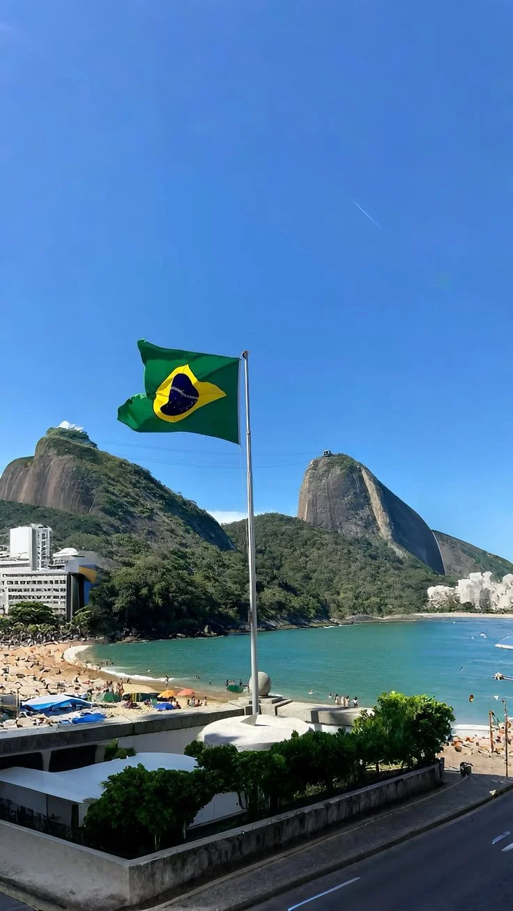 Bandera de Brasil onde se ve la playa, montañas y un cielo azul claro.