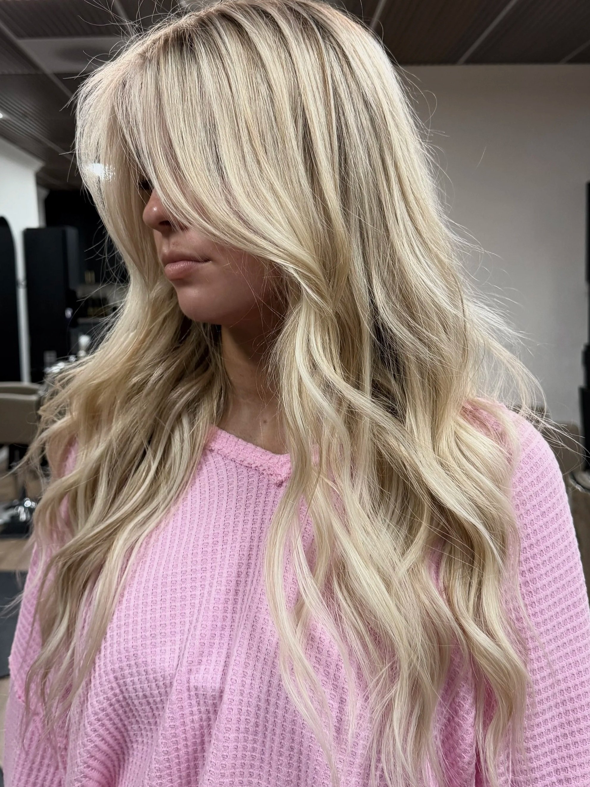 A woman with long, wavy blonde hair, K-Tip extensions, cool blonde hair.