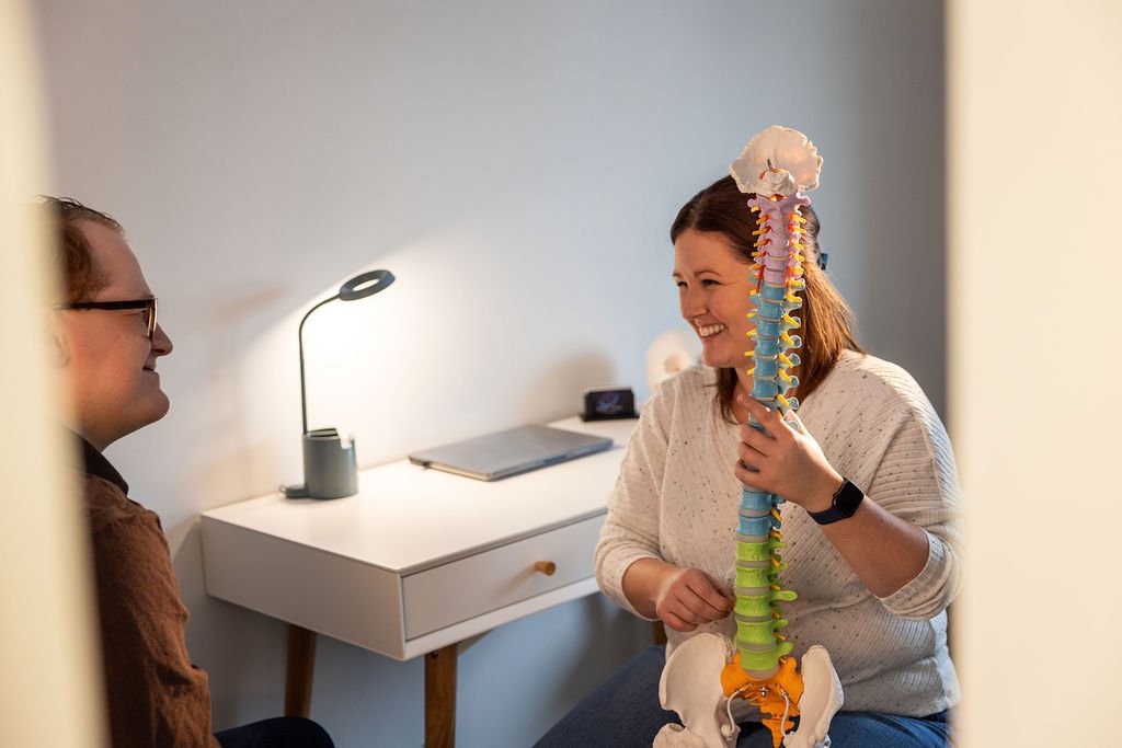 Stéphanie Ducharme, ostéopathe à Lévis, montre un modèle anatomique de la colonne vertébrale à un patient