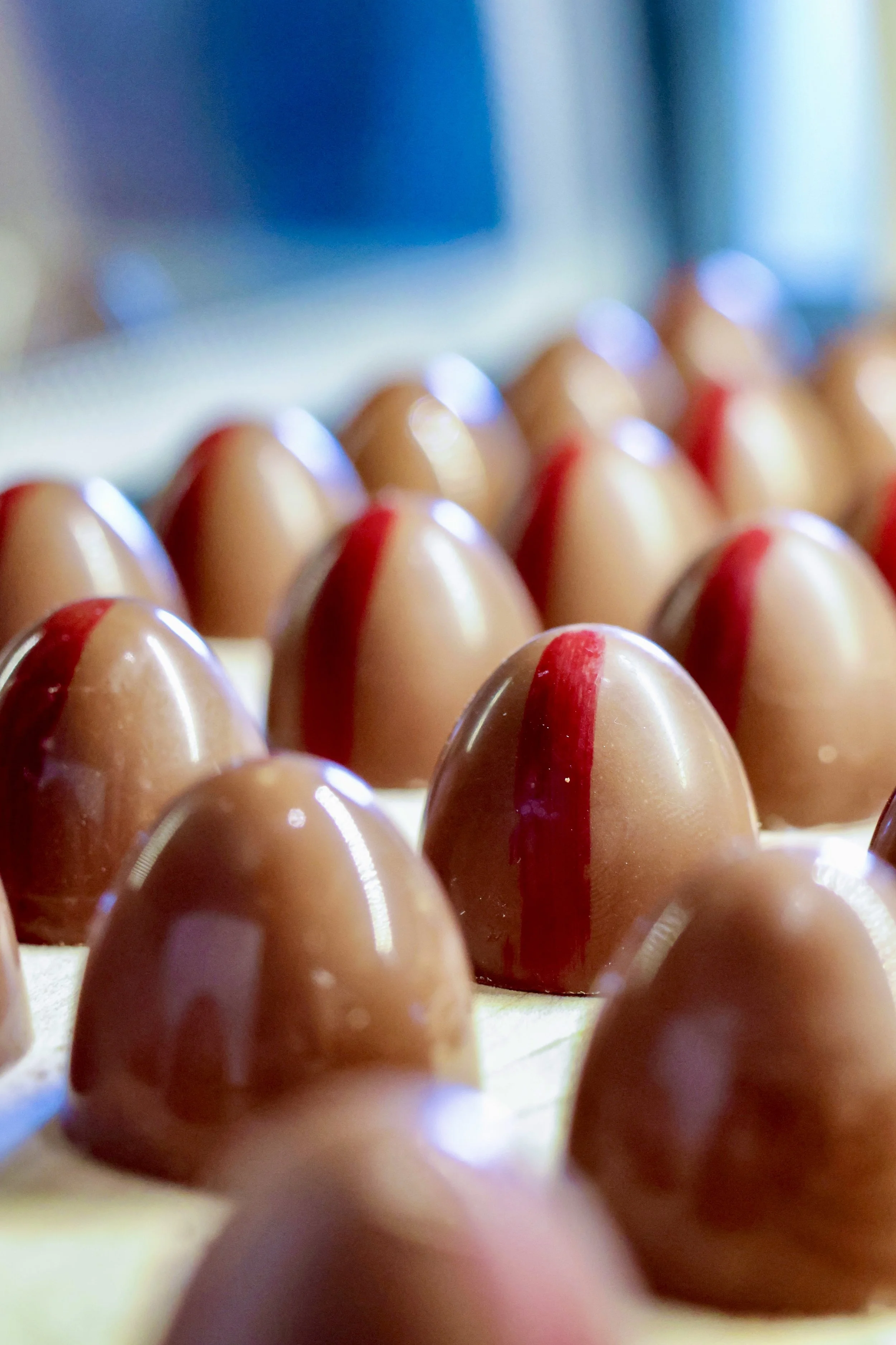 Close-up of light brown eggs with red lines, arranged in neat rows.