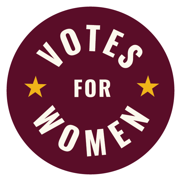 Round badge with a dark purple background and white text that says "Votes for Women." There are two gold stars, one on each side of the text.