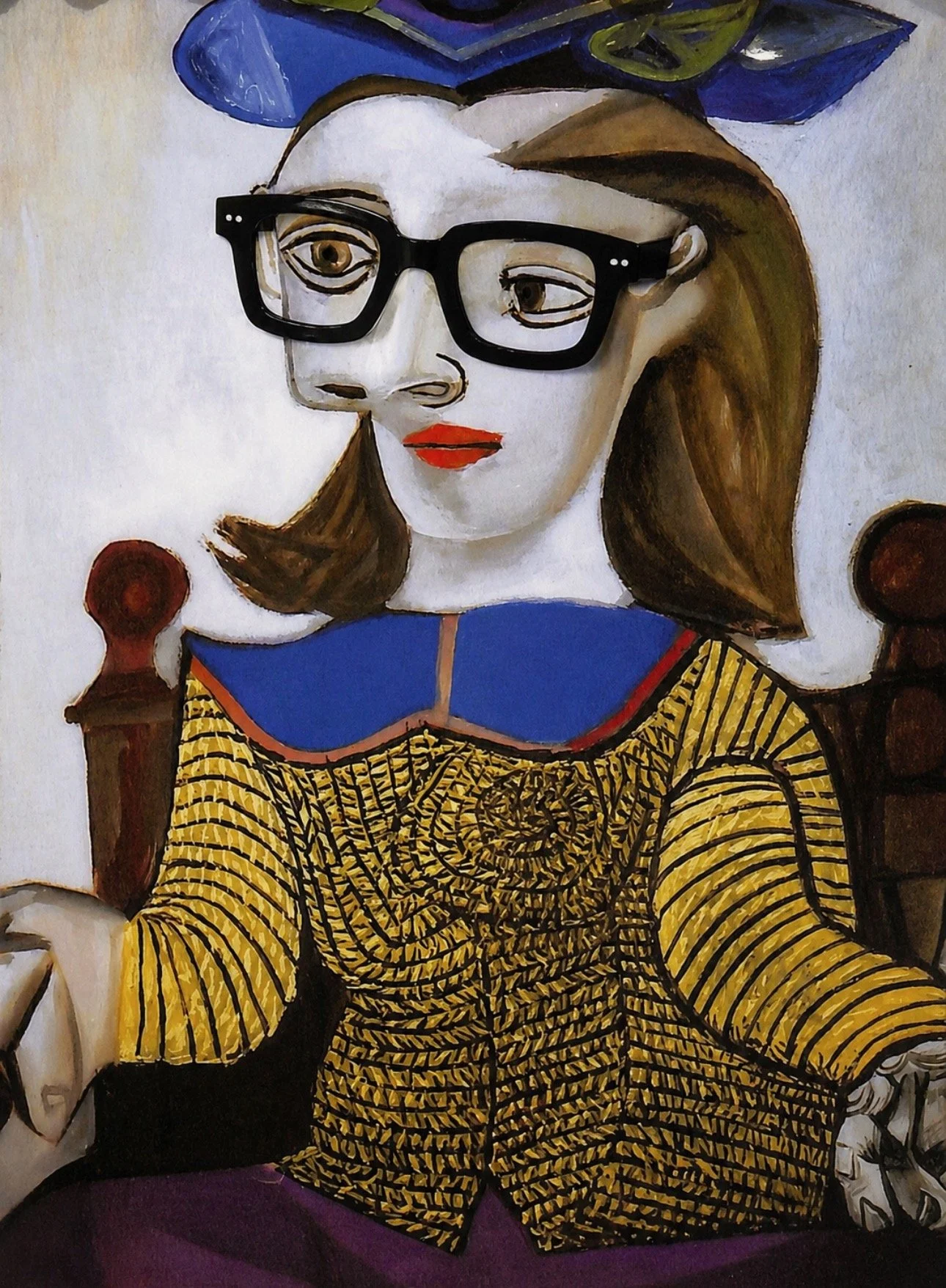 A woman with brown hair and red lipstick wearing black glasses, a blue collar, and a yellow patterned top, sitting in front of a painted backdrop that includes two wooden bedposts.