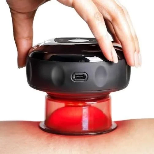 A hand holding a small black electronic device placed on a person's skin, with a red light or laser for therapy or medical treatment.