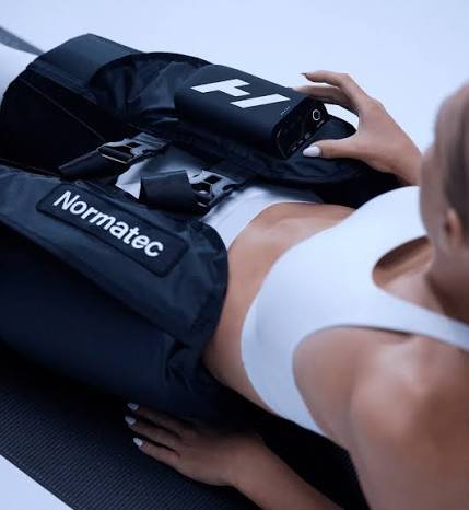 Person receiving a medical or physical therapy treatment with a device labeled 'F1' from 'Normatec' on their thigh.