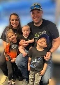 Family photo of two adults and three children smiling together