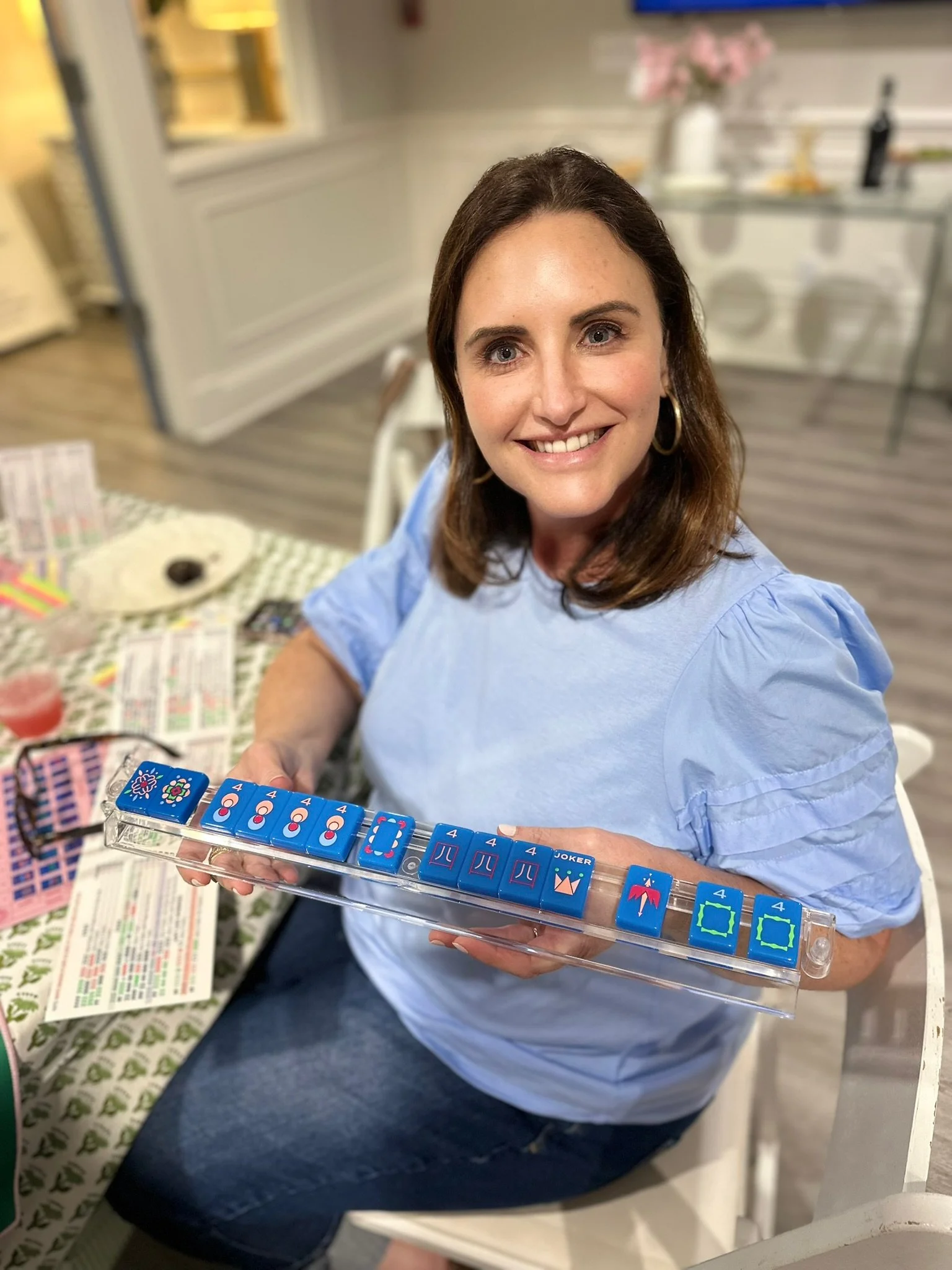 A woman smiling and after winning Mahjong with blue domino tiles.