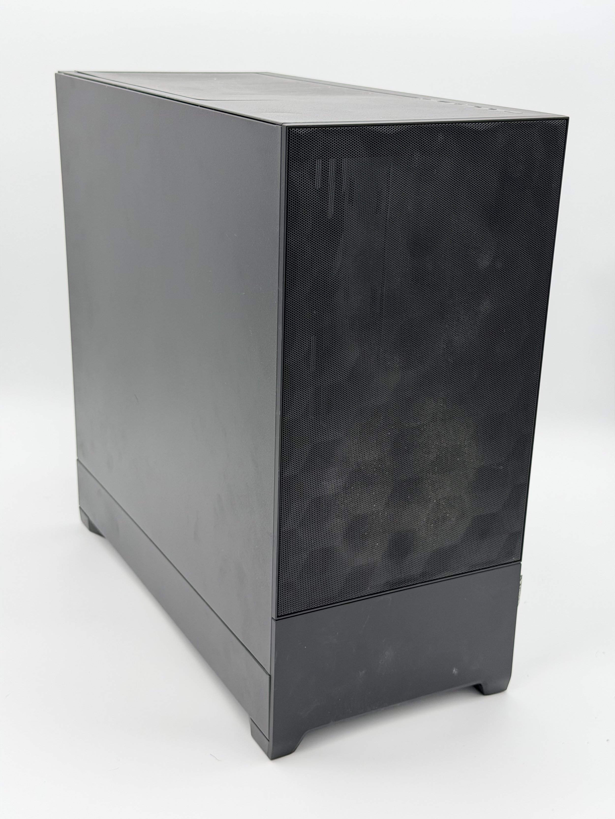 A large, black, rectangular desktop computer tower with a perforated front panel, placed on a white surface against a light background.