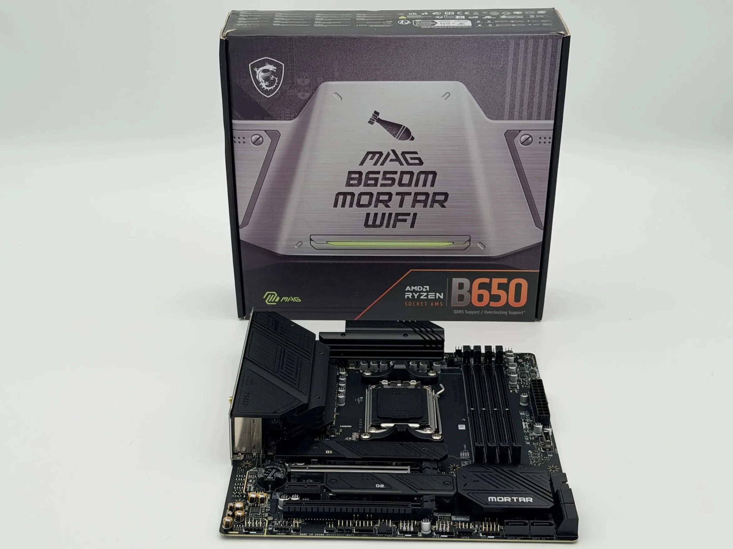 A computer motherboard and processor box on a white surface.