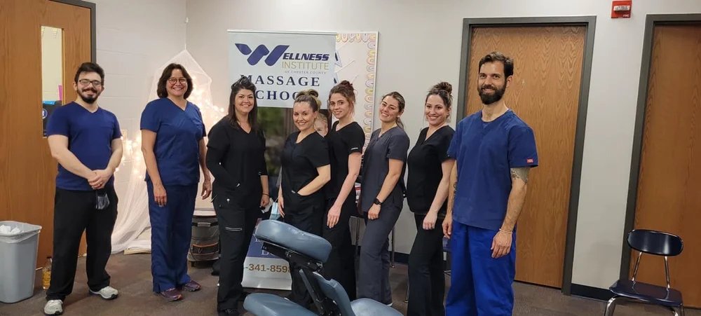 Group of seven healthcare professionals standing in a line inside a wellness clinic reception area, smiling for the photo.