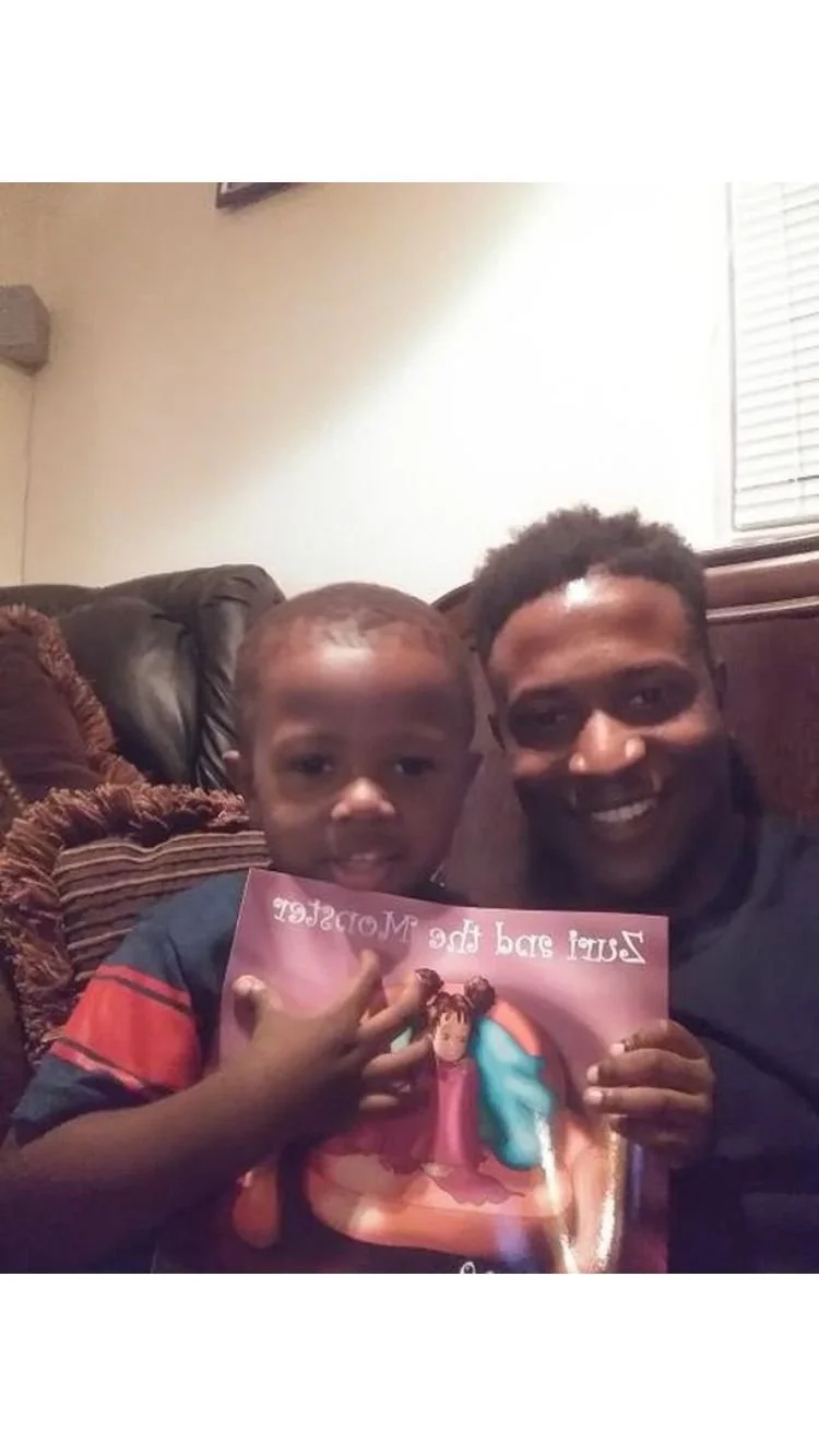 A man and a young boy sitting together on a couch, holding a colorful card with a princess on it and smiling at the camera.
