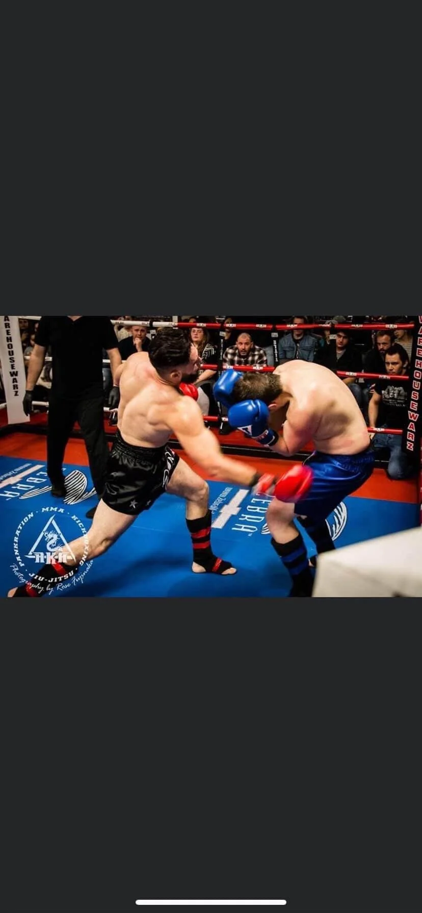 Two men in boxing gloves sparring in a boxing ring surrounded by spectators.