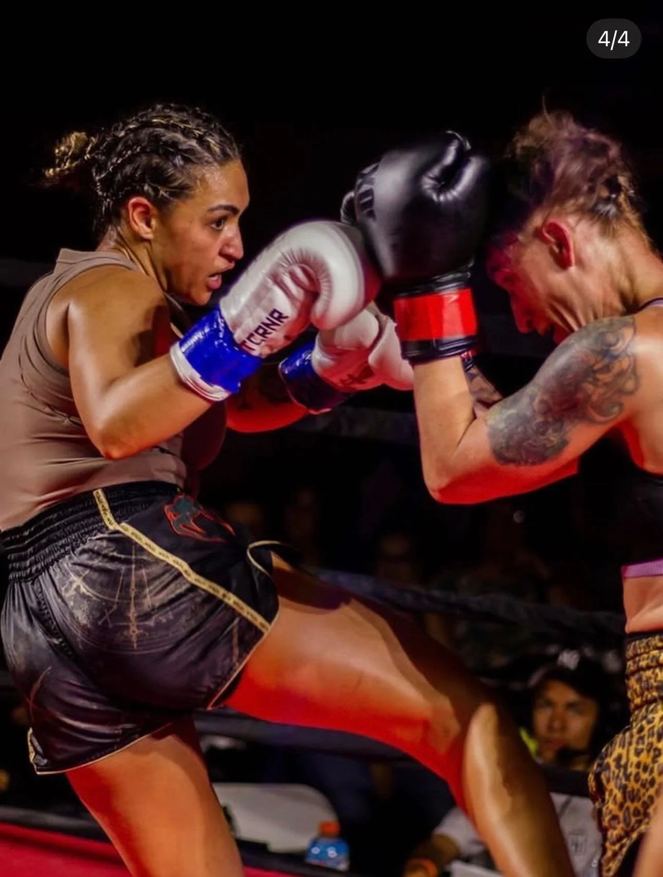 Two female fighters in a boxing match, one delivering a punch to the other's face in a boxing ring.