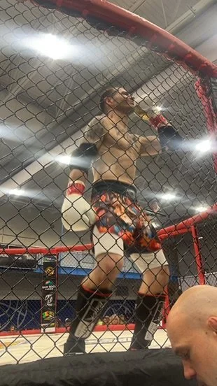 Mixed martial arts fighter in the ring drinking from a bottle.