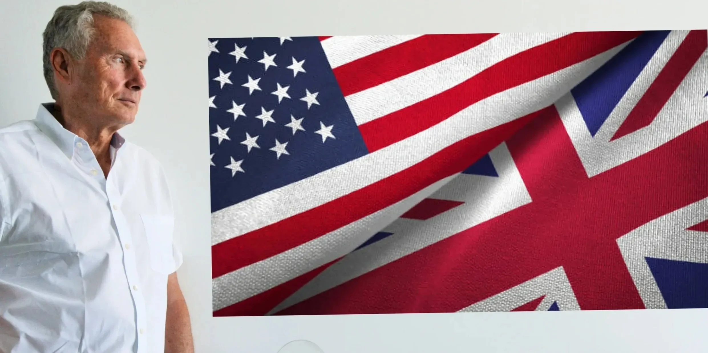 Side view of an older man with gray hair wearing a white shirt, standing next to a large American and British flag.