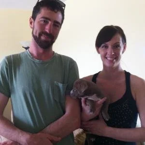 A man and woman holding a puppy together indoors.