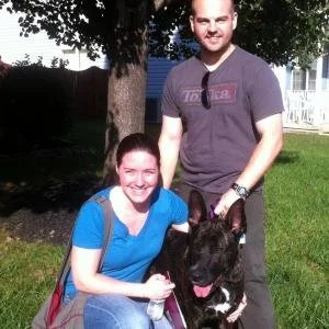 A young woman and a man with a black dog outdoors in a park