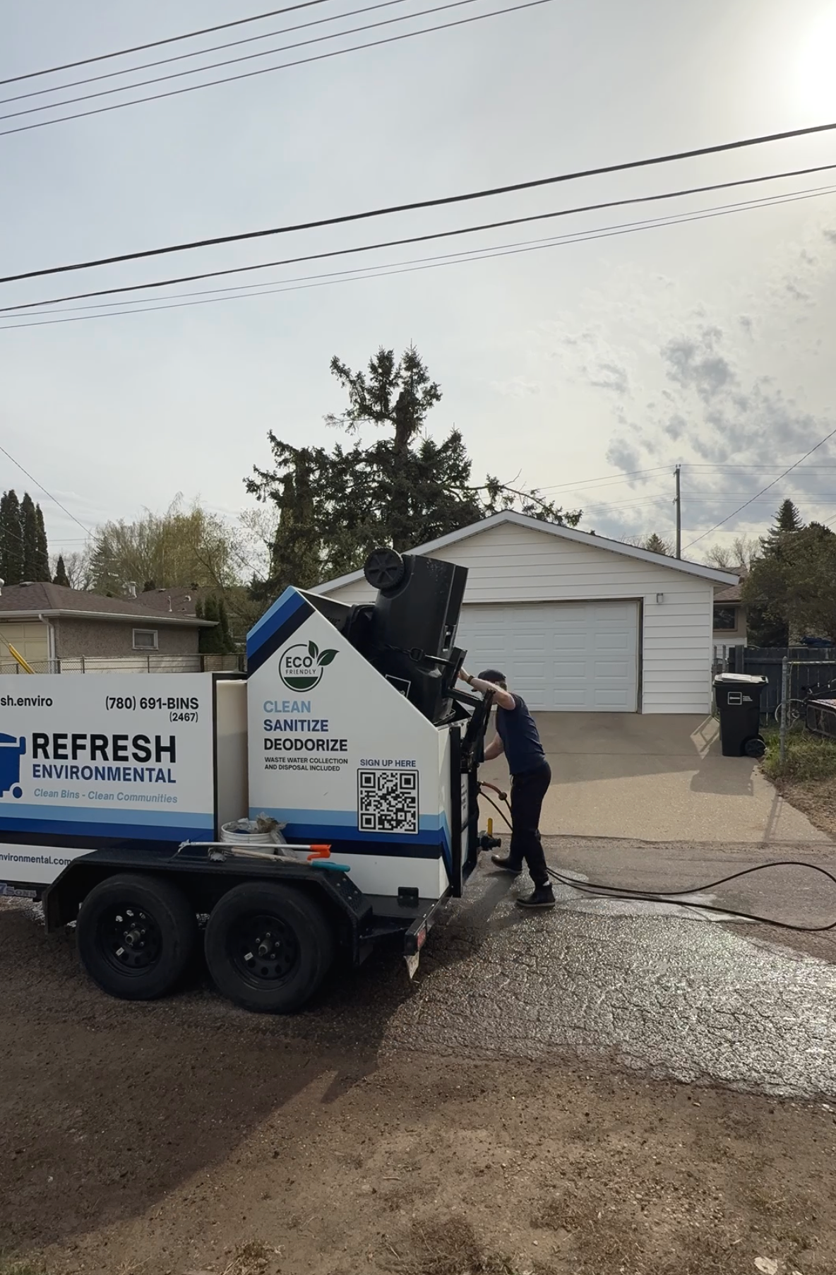 A photo of a man lifting a trailer onto a bin washing trailer