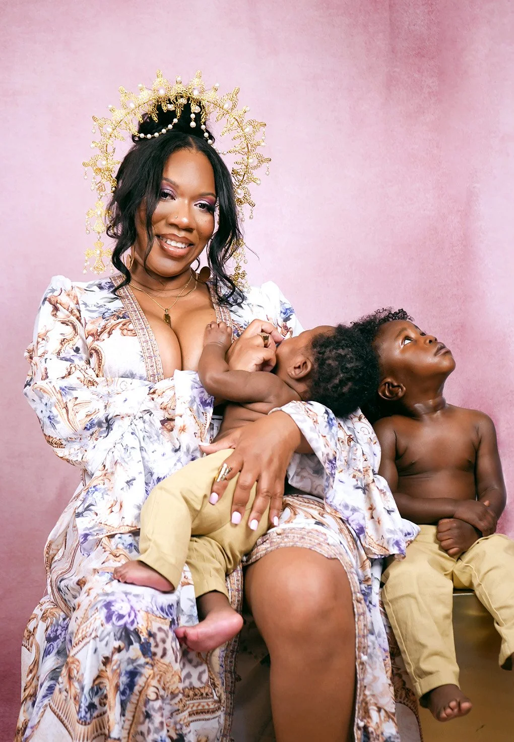 Photo of happy Black woman against a pink background sitting with her two children