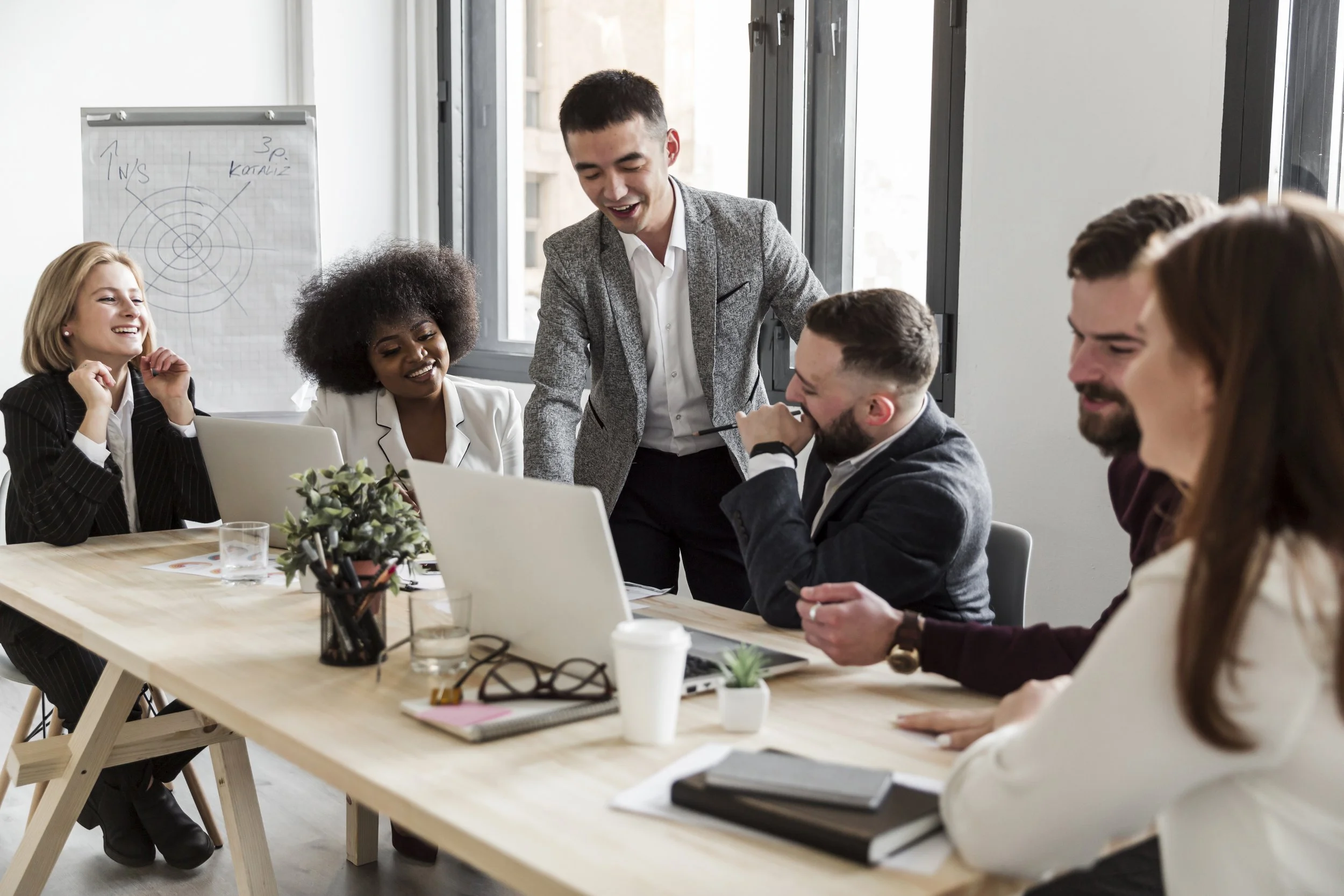 A diverse group of professionals in a leadership development workshop sitting at a conference table in a modern office.