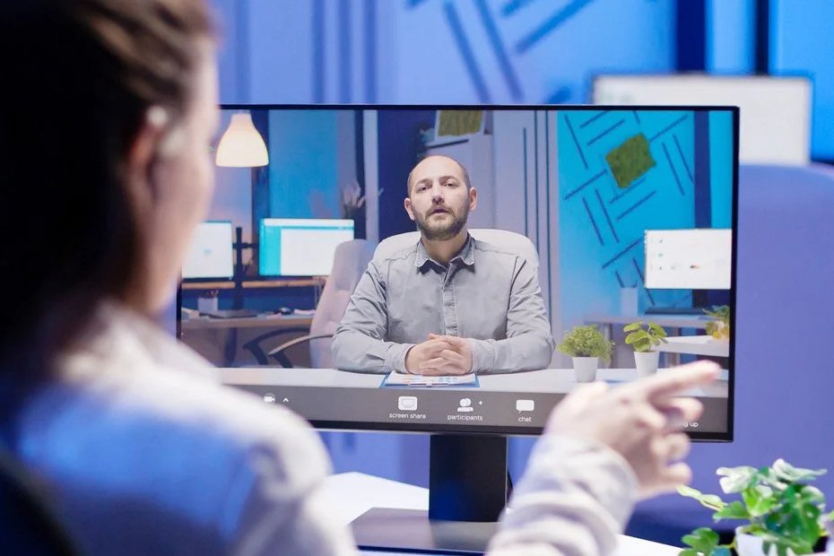 Person in front of a computer screen showing a video conference of an executive coaching session.