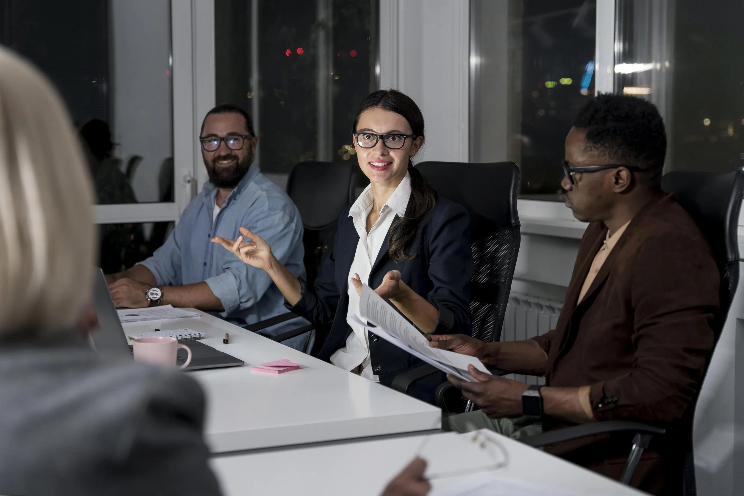 A diverse group of professionals in a leadership meeting sitting at a conference table in a modern office.