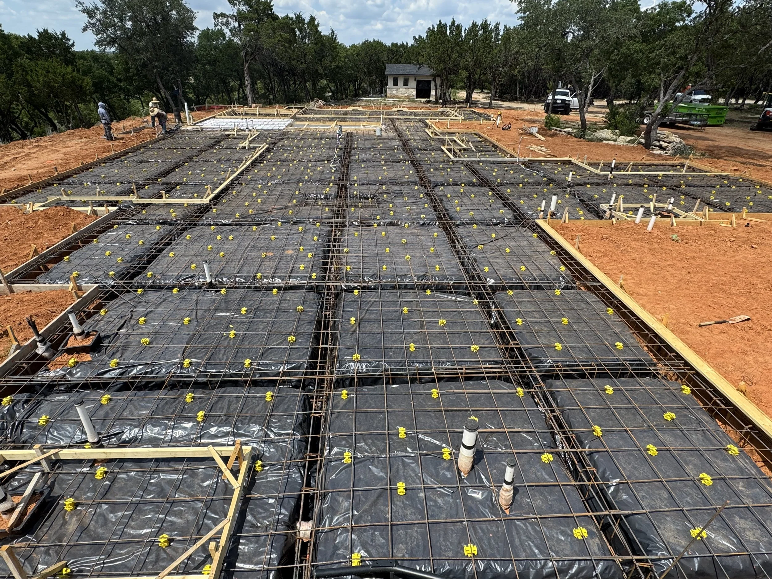 Home Construction site with steel rebar and yellow plastic rebar supports (UBS chairs). Black Poly, rebar, chairs, tie wire. Forming supplies for concrete slab.