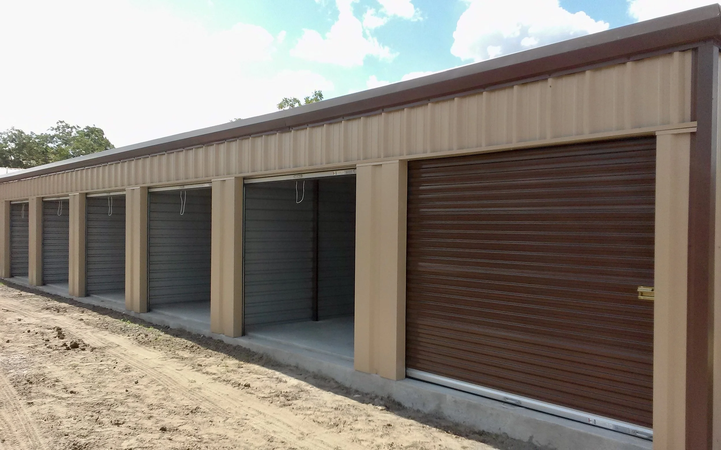 Mini-storage units with tan pbr panel walls, brown trim, and brown roll up storage doors.