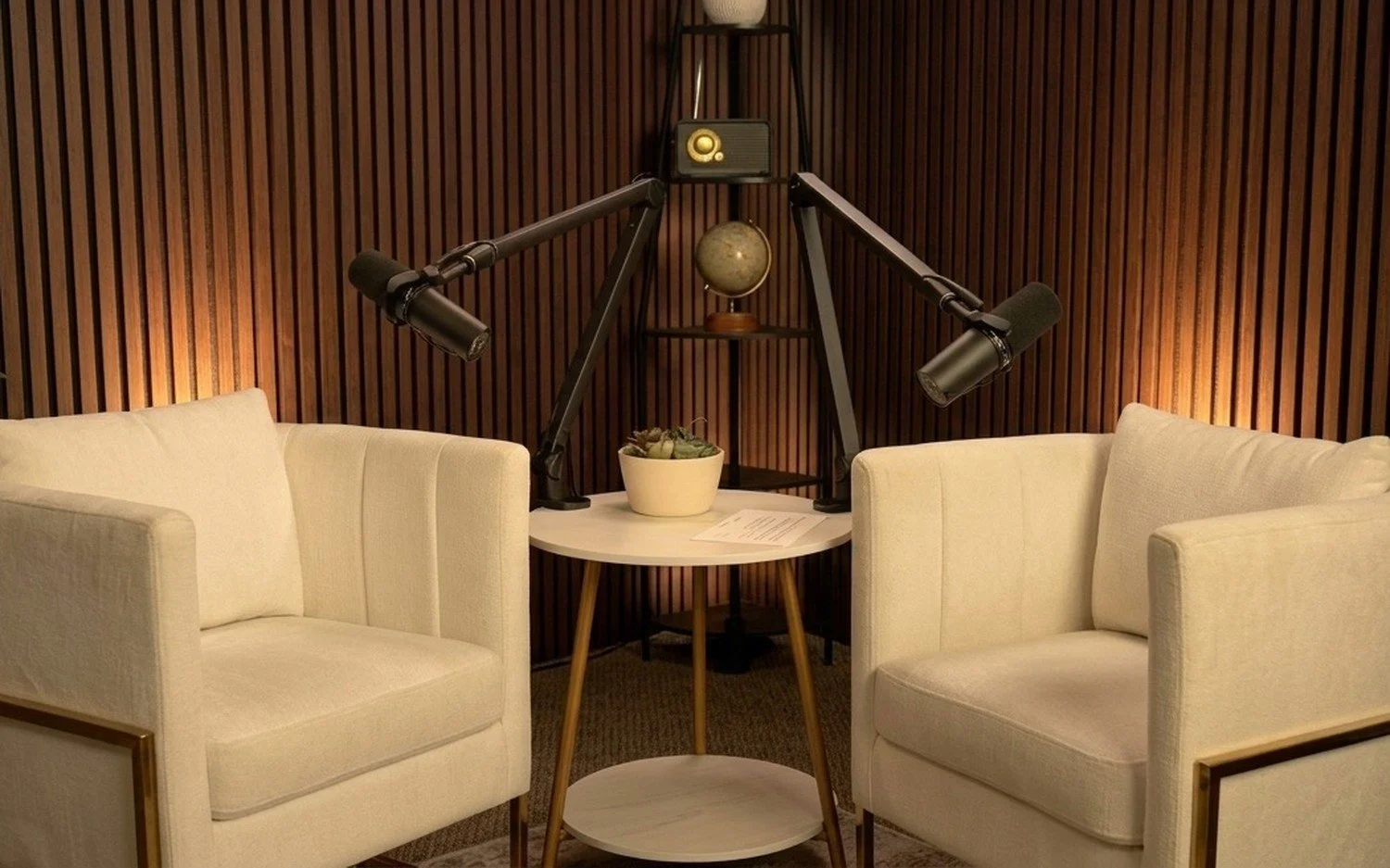 Interview set at Capital Podcast Studio with two armchairs, boom mics and a warm wood-slat wall