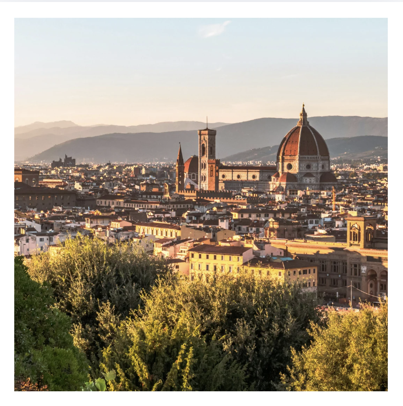 Sunset view of Florence, Italy, with the Florence Cathedral's dome and bell tower, surrounded by historic buildings and greenery.