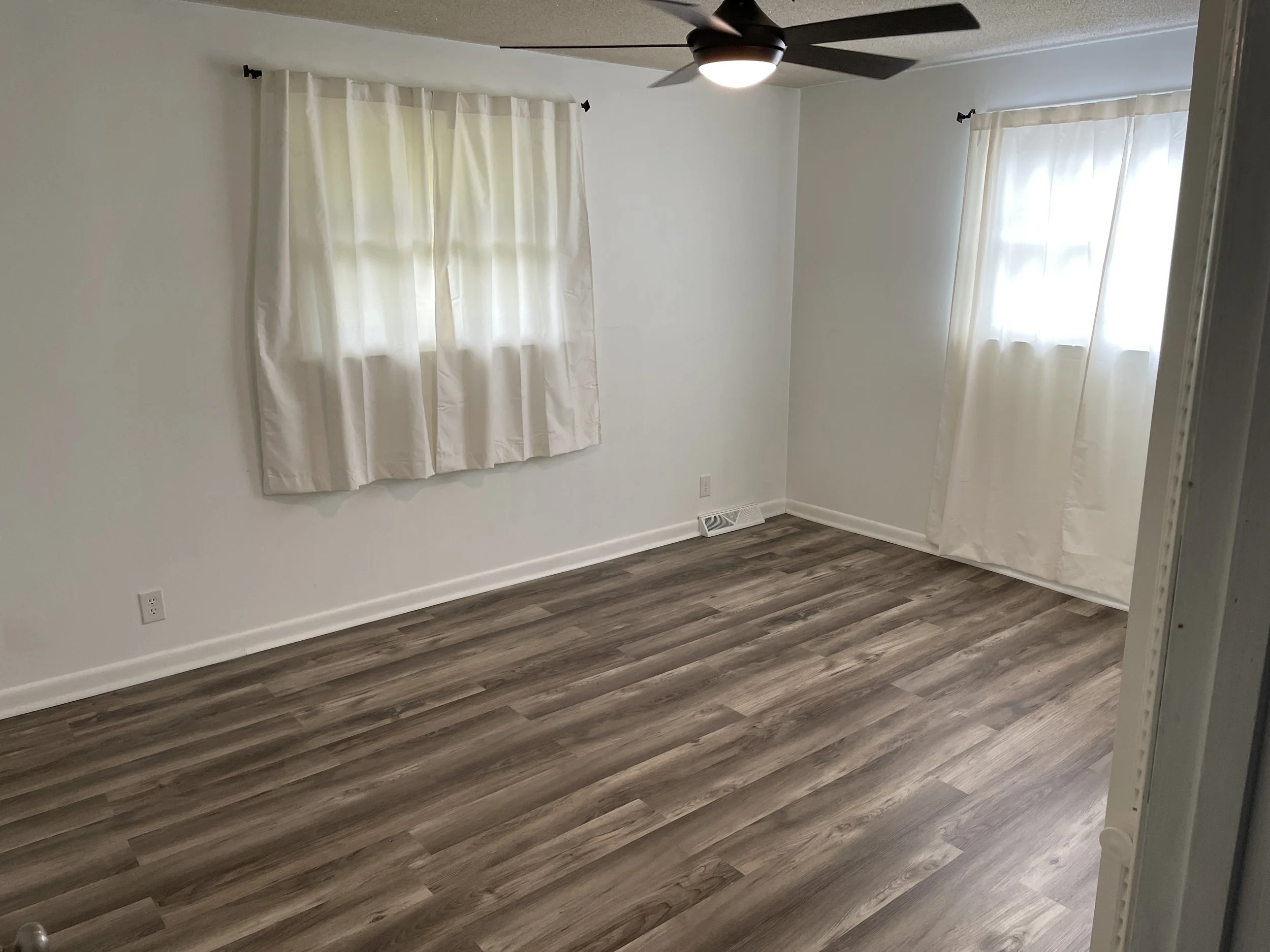 Completed wood-look laminate flooring installation in a bedroom for a military PCS move-out by All Phase Flooring LLC in Clarksville, Tennessee.