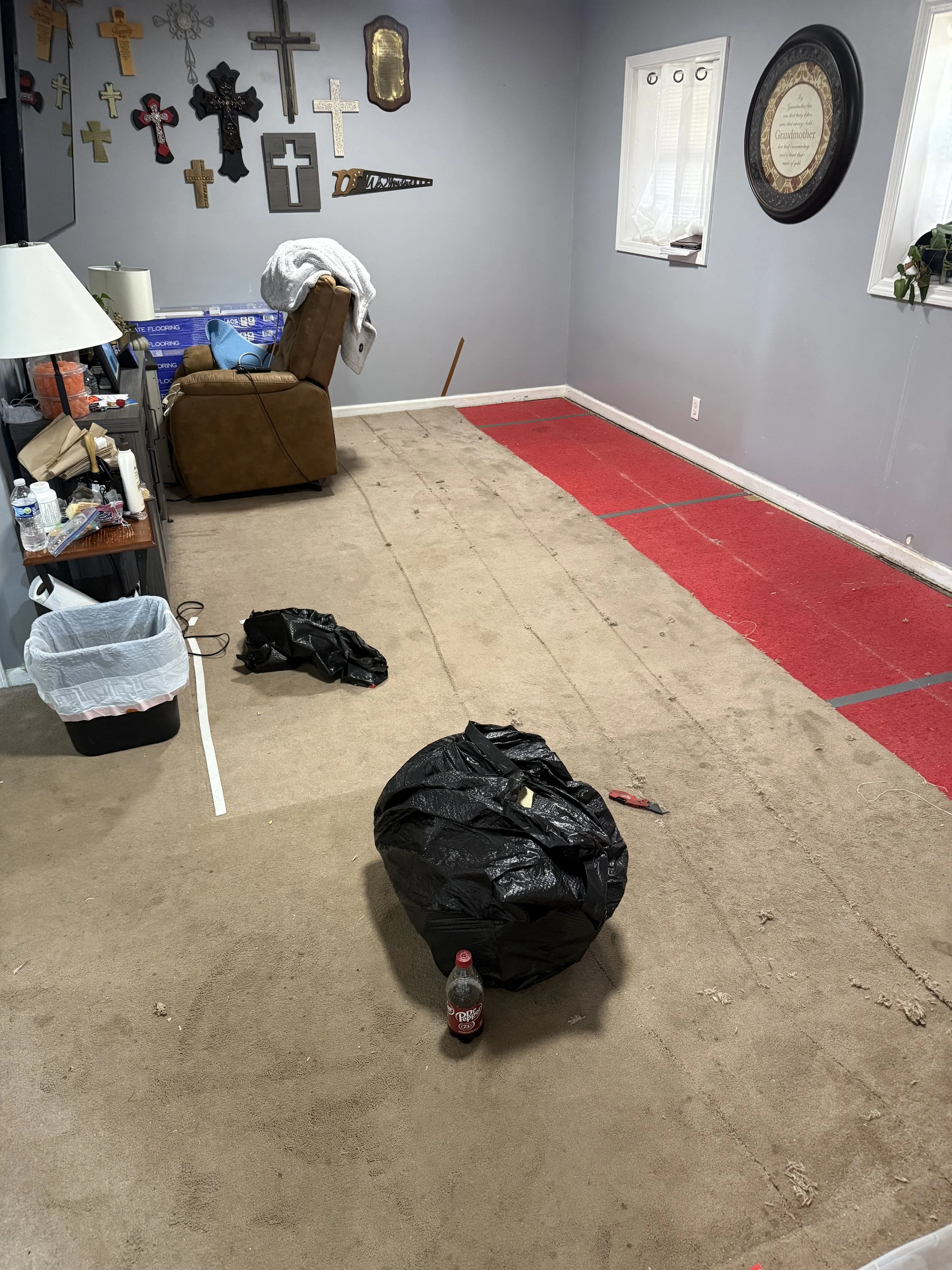 Living room floor showing old carpet and red carpet padding before removal during a PCS move-out project by All Phase Flooring LLC near Fort Campbell.