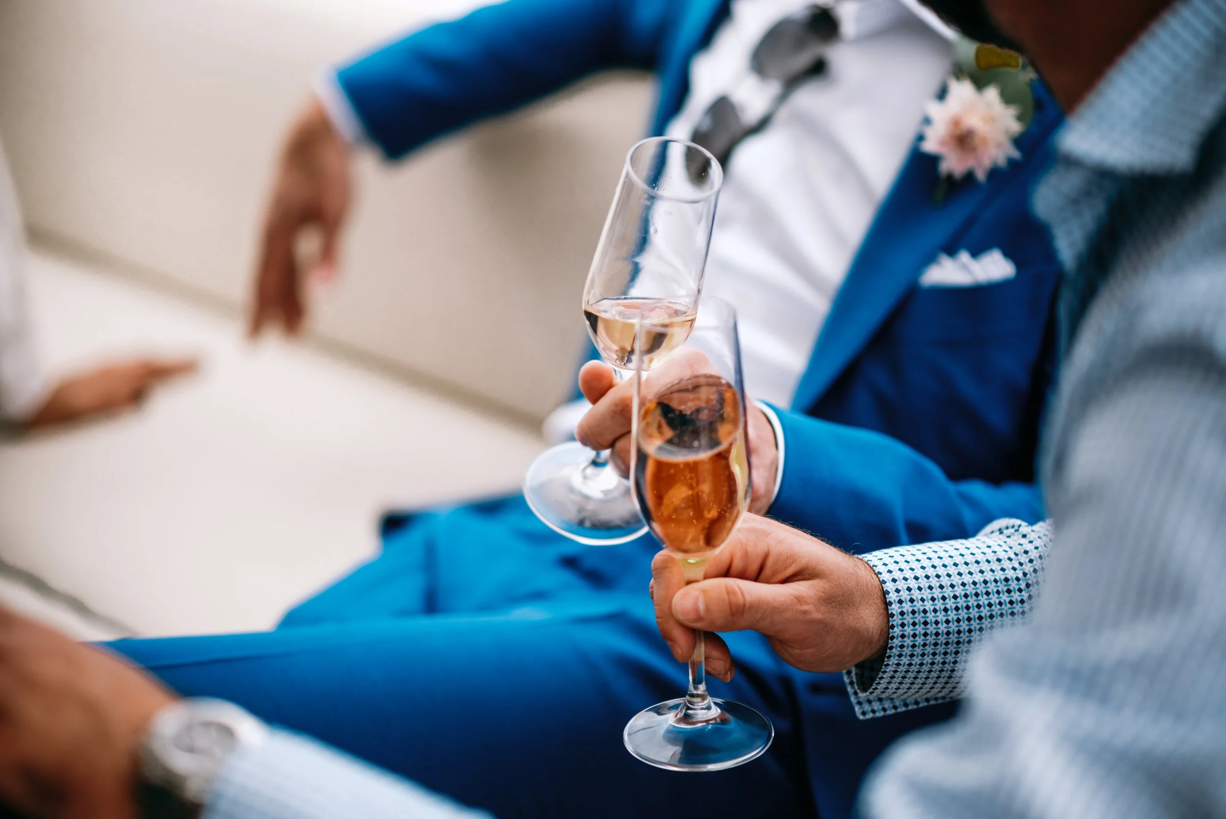 A person in a blue suit holding a glass of champagne.