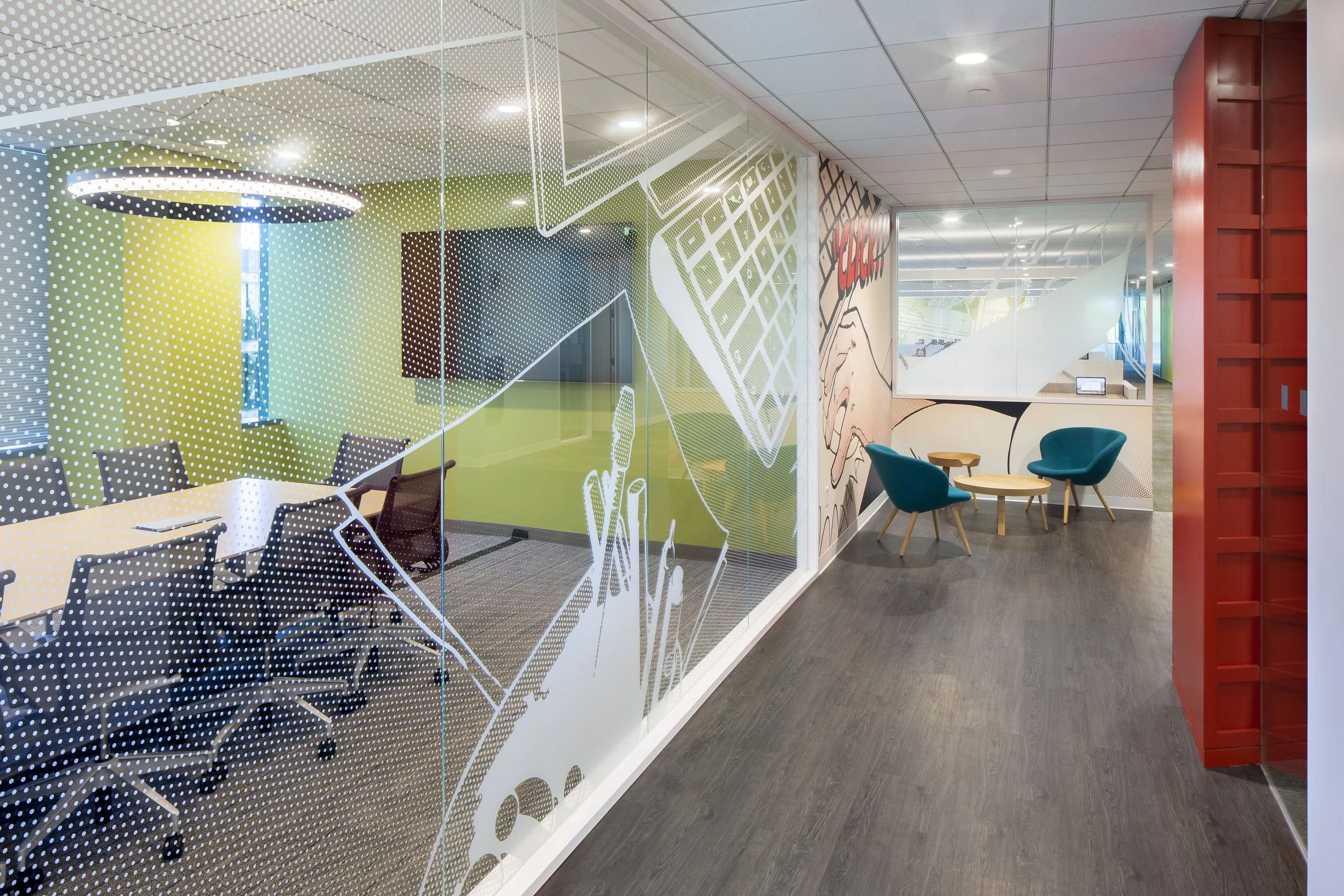 Interior view of an office with colorful chairs, small tables, and a wall decorated with comic book style artwork. 