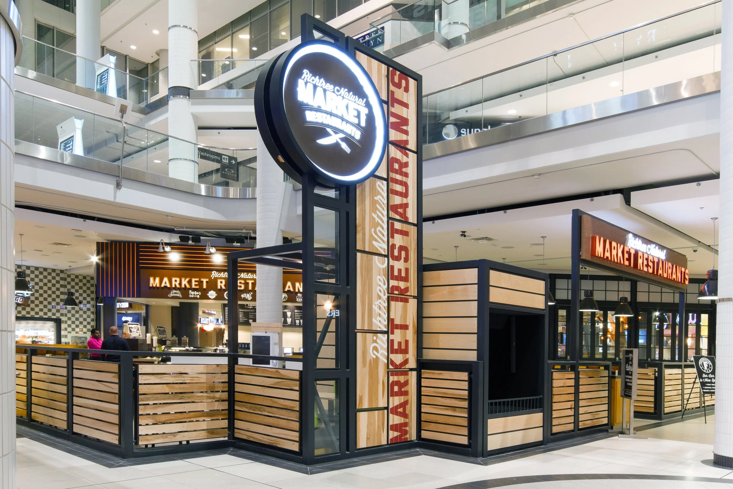 Indoor market eatery with a circular illuminated sign reading 'Richree Natural Market'. 