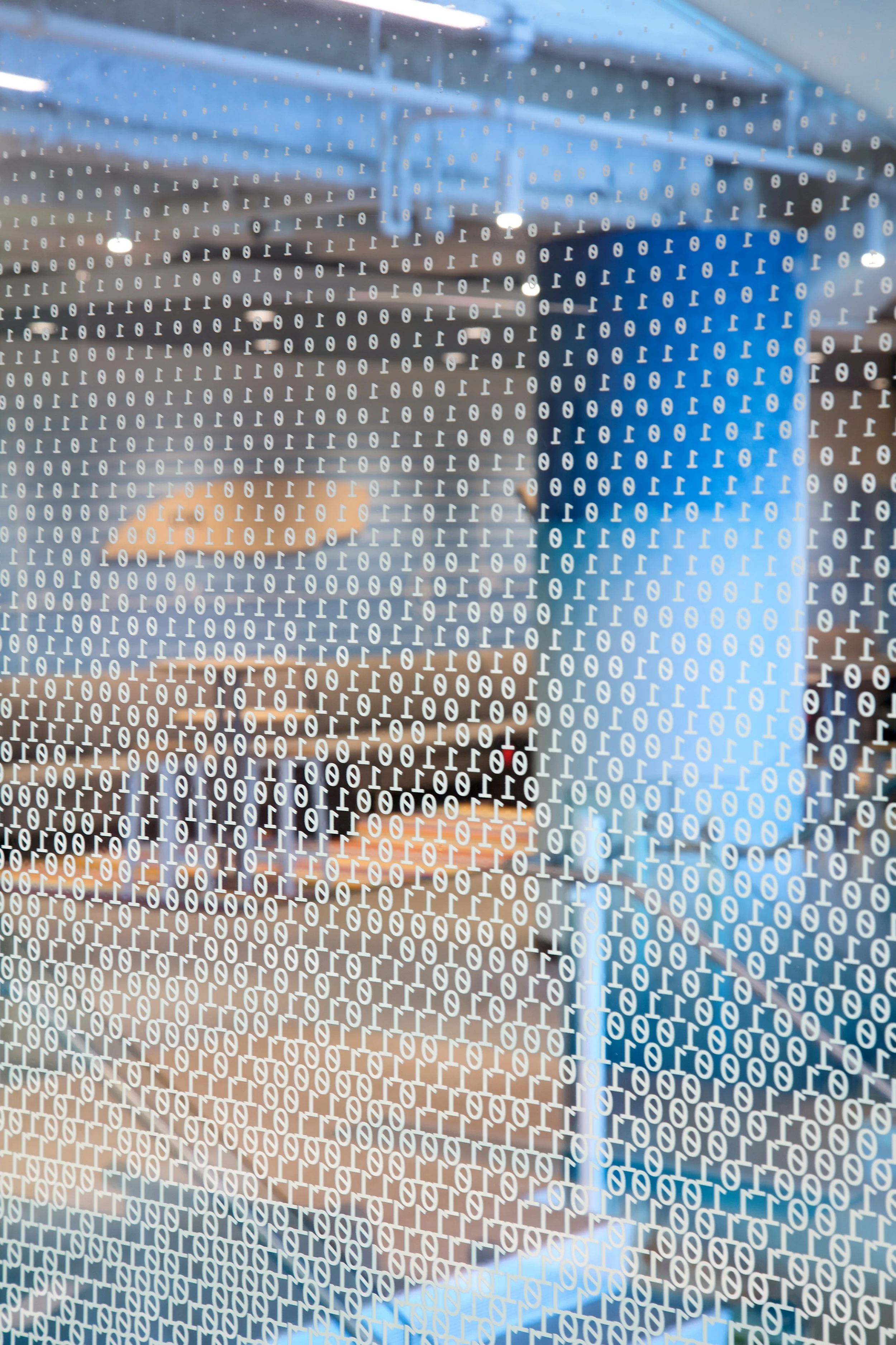 Reflection of a room on a glass surface with binary code overlay.