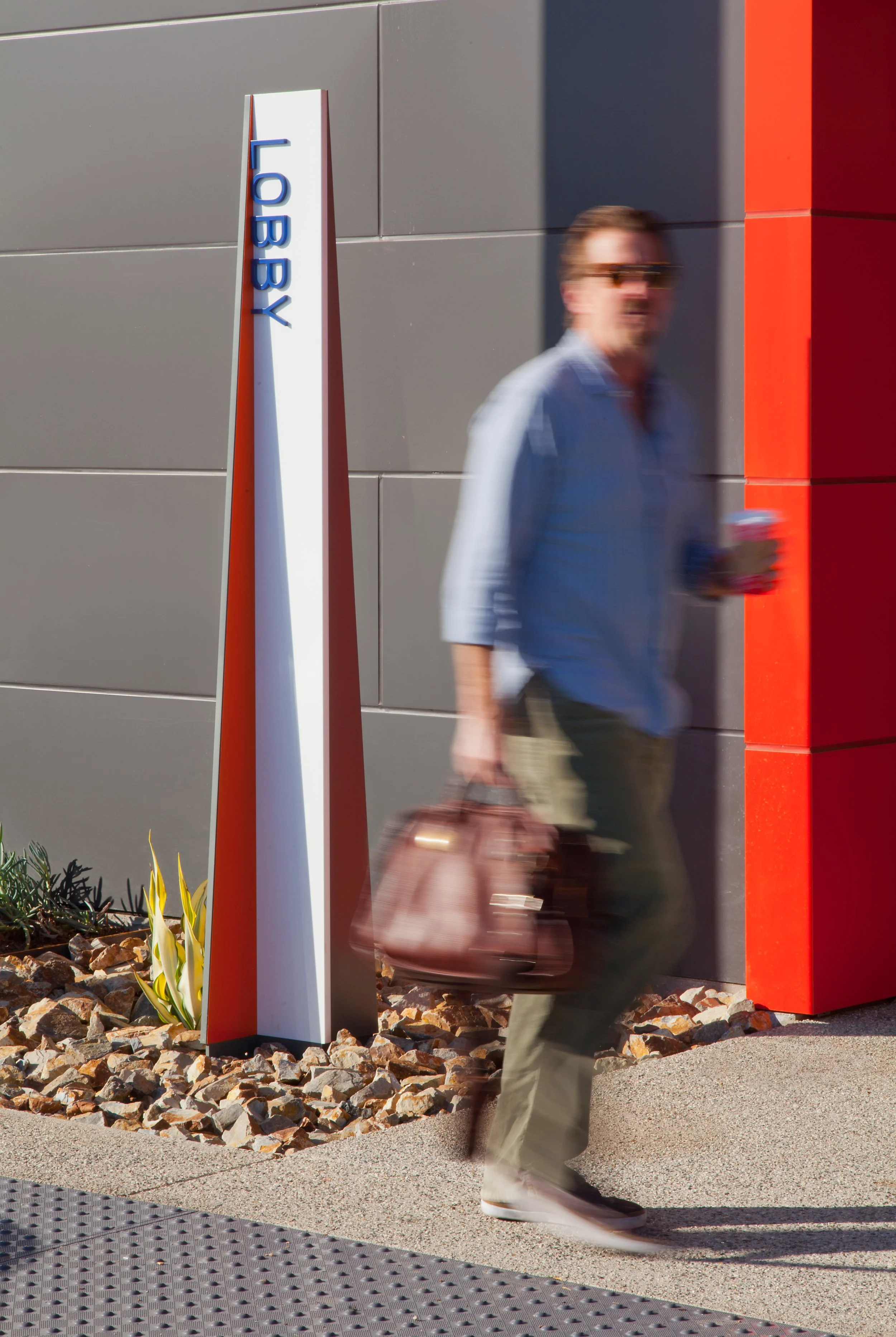 A person walking past a sign that reads "LOBBY" on a white vertical stand. 