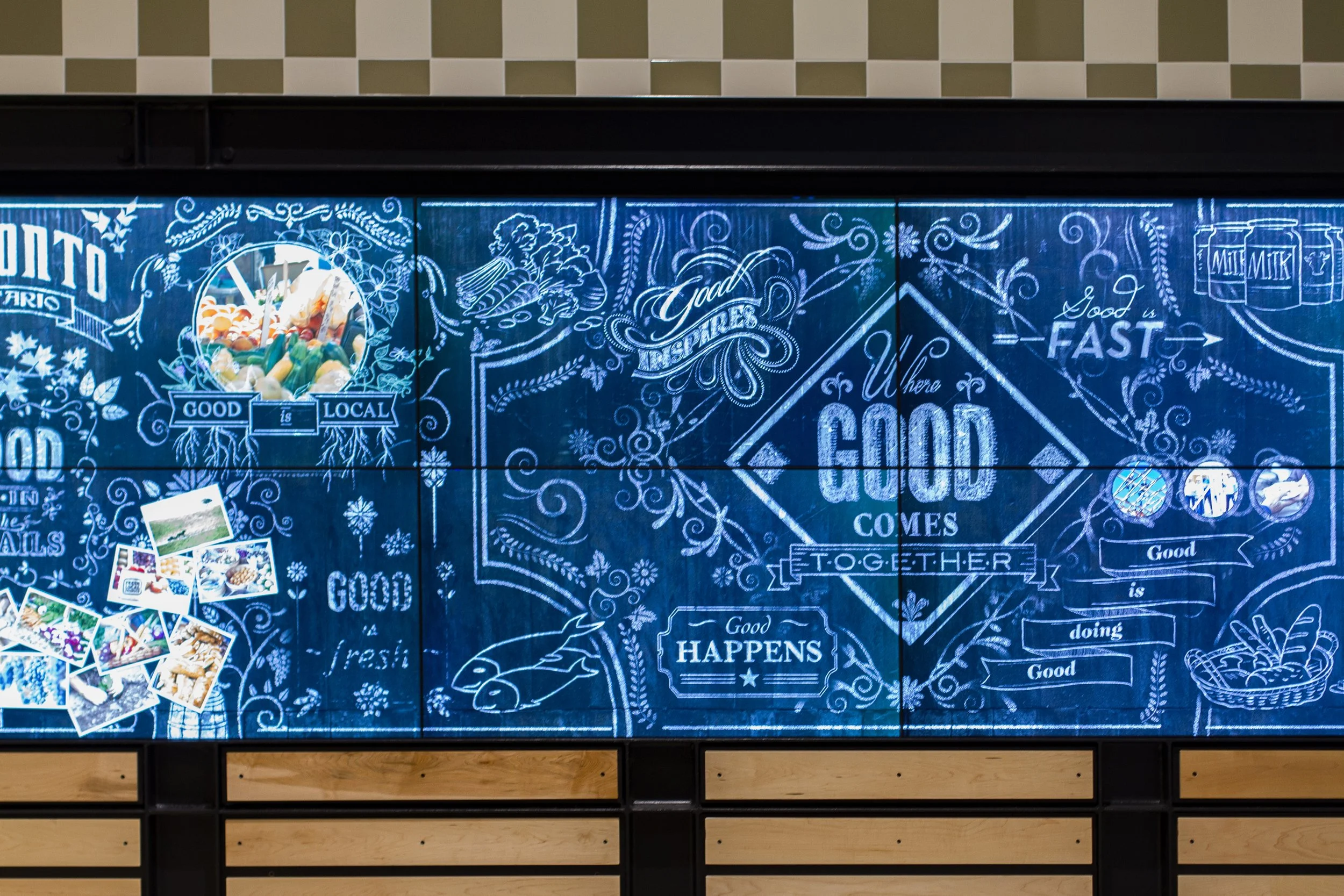 A decorative blue chalkboard with white text and illustrations promoting local foods and good eating habits, accompanied by a small pile of colorful photos.