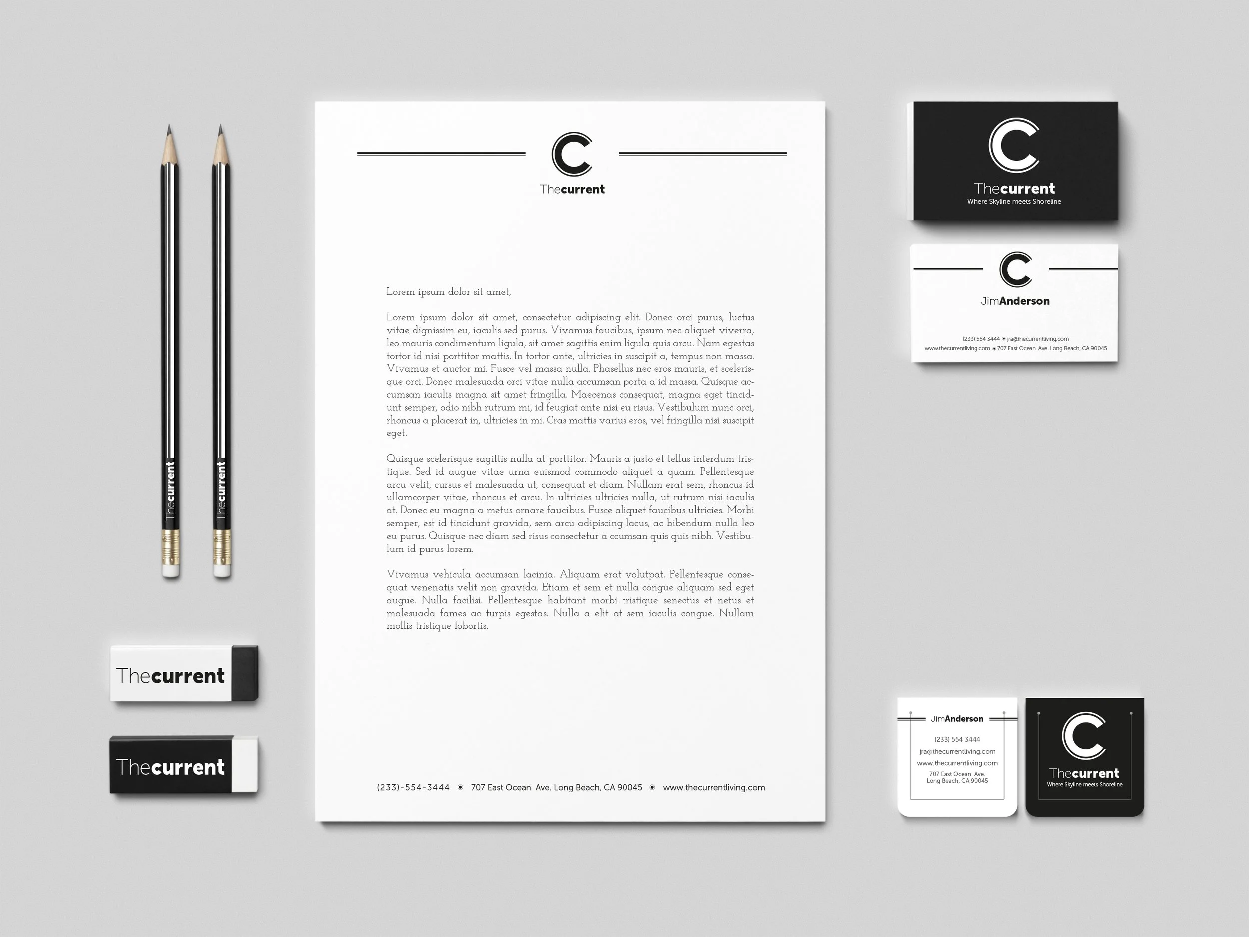 A collection of business stationery items for 'The Current,' including two pencils, a letterhead, two business cards, an eraser, and a small notepad, all in a precise, minimalist black-and-white design on a light gray background.