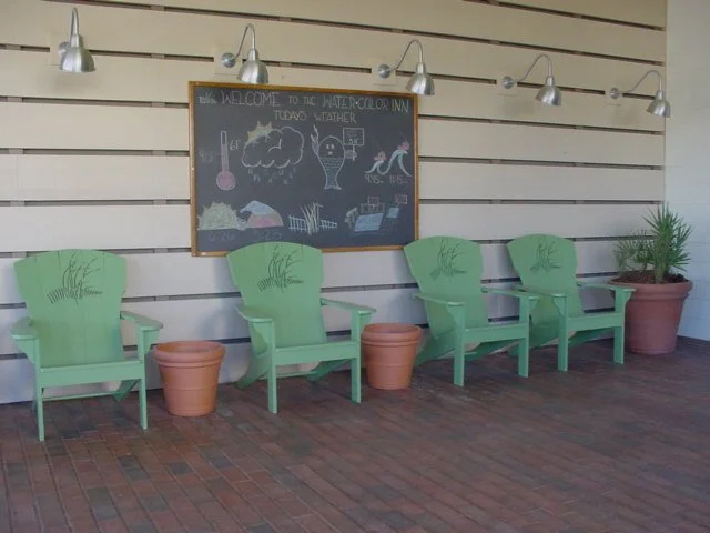 Four green chairs with two empty terracotta flowerpots between them